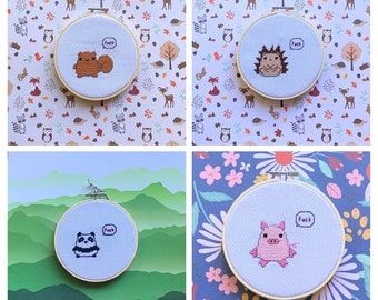 May include: Four embroidery hoops with different designs. Each hoop has a white background and features a different animal with the word "F*ck" in a speech bubble. The animals are a raccoon, a hedgehog, a panda, and a pig.