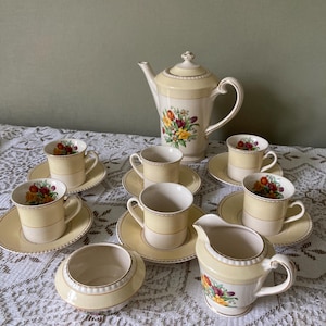 Puede incluir: Un juego de té vintage con un patrón floral amarillo y blanco. El juego incluye una tetera, una jarra de crema, un azucarero y seis tazas y platillos.