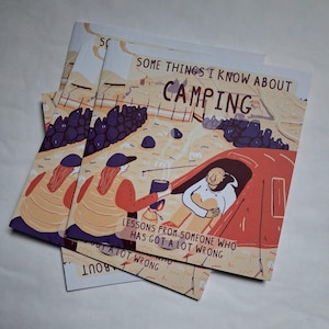 Puede incluir: Varios ejemplares de un libro cuadrado con temática de camping. La portada presenta ilustraciones de personas acampando, una tienda de campaña y el texto "SOME THINGS I KNOW ABOUT CAMPING". También se ve el texto "LESSONS FROM SOMEONE WHO HAS GOT A LOT WRONG".