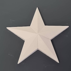 May include: A white, five-pointed star made of plaster or ceramic. The star has a three-dimensional, slightly textured surface.