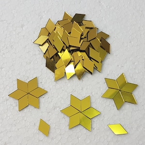 May include: A pile of gold mirror tiles, some of which are arranged into star shapes.