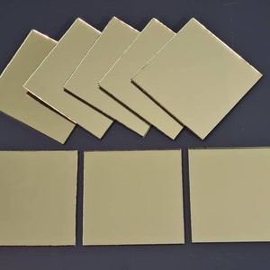 Puede incluir: Nueve azulejos de espejo cuadrados dorados. Los azulejos están dispuestos en tres filas de tres.