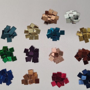 Könnte beinhalten: Sortiment von 12 kleinen quadratischen Spiegelkacheln in verschiedenen Farben, darunter Gold, Silber, Rot, Blau, Grün und Lila.