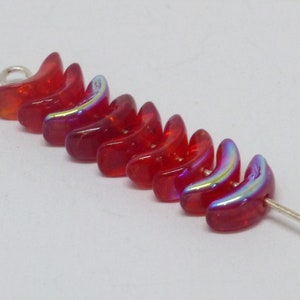 May include: A strand of red iridescent glass beads in the shape of crescent moons. The beads are strung on a silver wire.