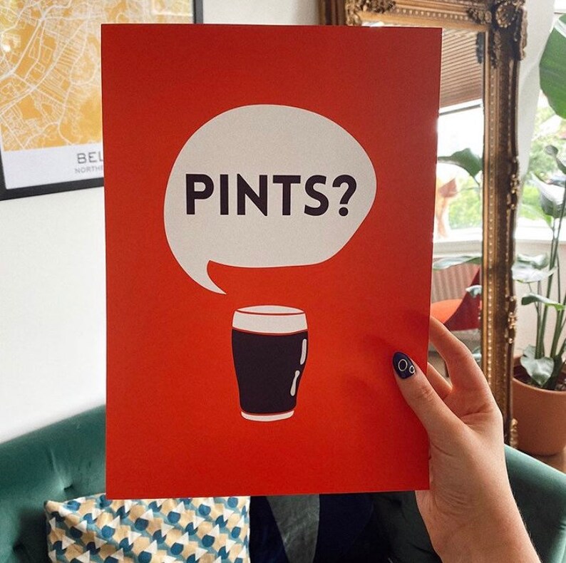 Puede incluir: Un cartel rojo con una burbuja de di&aacute;logo blanca que contiene la palabra "PINTS?" en negro. Debajo, un vaso de pinta negro. El cartel est&aacute; sostenido por una mano.