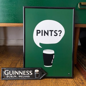Puede incluir: Un letrero verde enmarcado con el texto "PINTS?" en un bocadillo blanco y una ilustraci&oacute;n de vaso de pinta en blanco y negro. Tambi&eacute;n hay un letrero de metal negro con "GUINNESS DUBLIN, IRELAND".