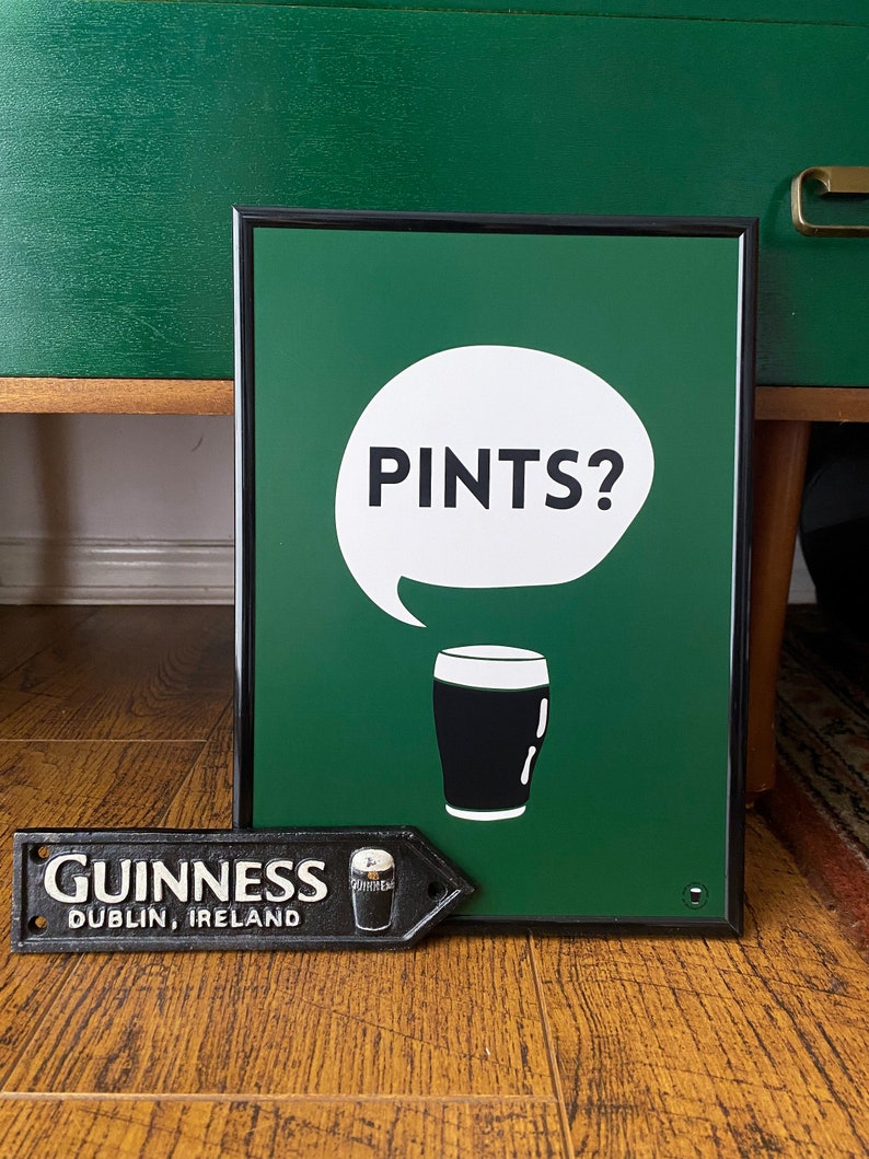 Puede incluir: Un letrero verde enmarcado con el texto "PINTS?" en un bocadillo blanco y una ilustraci&oacute;n de vaso de pinta en blanco y negro. Tambi&eacute;n hay un letrero de metal negro con "GUINNESS DUBLIN, IRELAND".