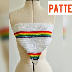 Op de afbeelding: Witte gehaakte top met een regenboogstreepontwerp. De top wordt op een mannequin getoond. Het woord "PATTERN" staat in een rode doos rechtsboven. De onderkant van de top is een driehoek.