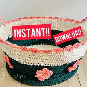 May include: A handmade crochet basket in cream, dark green, and coral. The basket features a scalloped edge and handles, with floral embellishments. The text "INSTANT!! DOWNLOAD" is displayed on a red banner. The word "Crochetlyn" is written at the bottom.