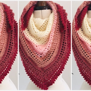 Puede incluir: Un chal de ganchillo con un degradado de colores desde rojo oscuro hasta crema. El chal tiene un delicado borde de encaje.