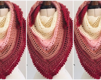 May include: A crocheted shawl with a gradient of colors from deep red to cream. The shawl has a delicate lace border.
