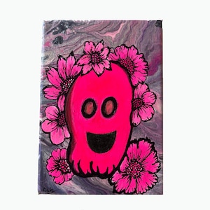 May include: A pink skull with a smiling face surrounded by pink flowers on a gray and black marbled background.