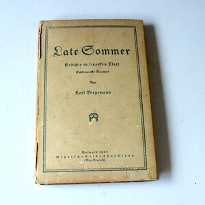 Könnte beinhalten: Ein altes Buch mit dem Titel "Late Sommer" mit deutschem Text auf dem Einband. Das Buch hat einen beigefarbenen Einband mit grünem Rand und schwarzem Text. Das Buch ist leicht abgenutzt, was auf sein Alter hindeutet. Titel und Autor sind deutlich sichtbar.