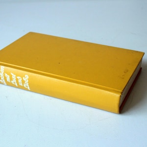 Könnte beinhalten: Ein Hardcover-Buch mit einem einfarbigen senfgelben Einband. Auf dem Buchrücken steht in weißer Schrift Roland Gööck Backen mit Lust und Liebe. Das Buch liegt schräg, sodass der vordere Einband und der Buchrücken auf einer schlichten Fläche zu sehen sind.