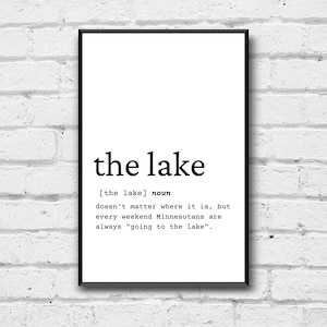 May include: Black and white typography print with the word "the lake" defined as a noun. The definition reads "[the lake] noun doesn't matter where it is, but every weekend Minnesotans are always "going to the lake".