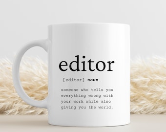 Może przedstawiać: Biały kubek ceramiczny z czarnym nadrukiem, na którym widnieje napis "editor" oraz definicja: "[editor] rzeczownik ktoś, kto mówi ci wszystko, co jest złe w twojej pracy, a jednocześnie daje ci świat."