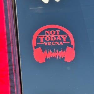 May include: Red sticker with the text "NOT TODAY VECNA" inside a headphone design. The sticker has a sound wave graphic at the bottom. A blue and white sticker is visible at the top.