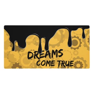 May include: A rectangular mat with a yellow background featuring a pattern of gears. Black paint drips from the top, with the words "DREAMS COME TRUE" in black font.