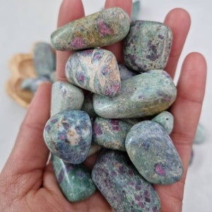 以下が含まれることがあります： 緑とピンクのルビーゾイサイトのタンブルストーンのコレクション。石は滑らかで磨かれており、緑とピンクの色合いがさまざまです。