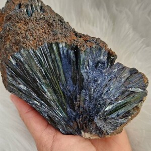 May include: A large, dark green and blue crystal cluster with a rough, brown exterior. The crystal points are sharp and iridescent, with a metallic sheen.