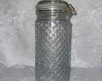 Bote alto de vidrio transparente con tapa hermética.