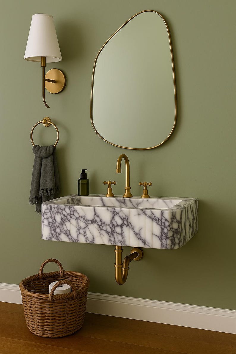 Pu&ograve; includere: Scena di bagno con lavabo in marmo, rubinetti dorati e specchio. Lampada da parete e portasciugamani visibili. Cesto in vimini sotto il lavabo. Il muro &egrave; verde.
