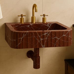 K&ouml;nnte beinhalten: Ein wandmontiertes, rechteckiges Waschbecken aus rotbraunem Marmor mit wei&szlig;en Adern. Das Waschbecken hat eine geriffelte Textur und ist mit goldfarbenen Wasserh&auml;hnen ausgestattet. Ein passendes Abflussrohr erstreckt sich darunter.