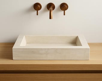 May include: A rectangular, light-colored stone sink with a bronze faucet and two matching handles. The sink is set into a wooden countertop with a matching wooden cabinet below. The fixtures are mounted on a white wall.