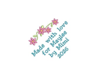Könnte beinhalten: Ein Stickmotiv mit einem geschwungenen grünen Stiel und vier rosa Blüten mit gelben Mitten. Der Text Made with love for Maylee by Mimi 2026 ist in hellblauem Garn diagonal unter dem Blumenmotiv auf einem weißen Hintergrund gestickt.