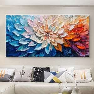 Peut inclure: Une grande peinture abstraite rectangulaire d'une fleur en pleine floraison. Les pétales passent du bleu profond au blanc, puis à l'orange et au rouge. L'œuvre est encadrée et accrochée au-dessus d'un canapé blanc.