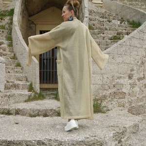 May include: A beige knitted long sleeve cardigan with a loose fit.