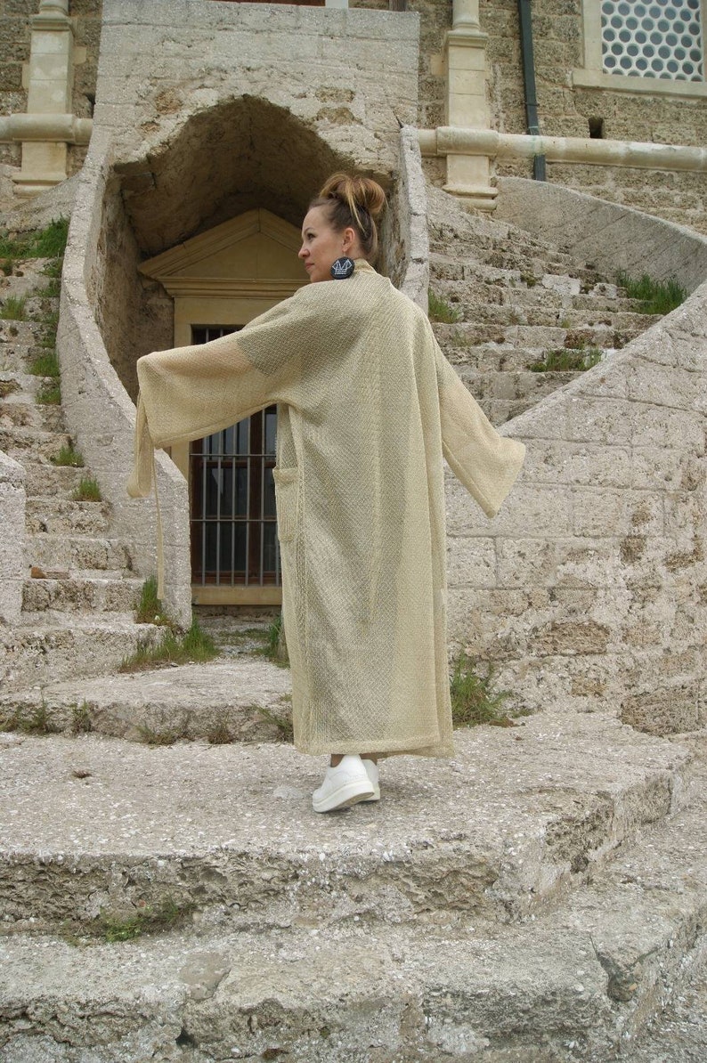 May include: A beige knitted long sleeve cardigan with a loose fit.