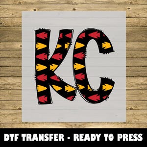 May include: A red and yellow patterned iron-on transfer design that says "KC".