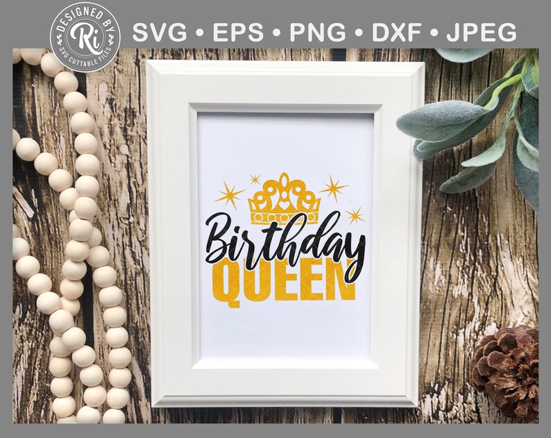 May include: White framed print featuring the text "Birthday QUEEN" in black and gold, with a gold crown and stars. The image is set against a backdrop of wooden textures and decorative elements.