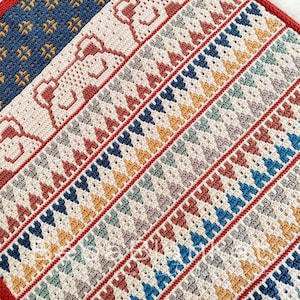 May include: A crocheted blanket with a geometric pattern in shades of red, blue, yellow, and white.