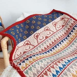 May include: A crocheted blanket with a geometric pattern in shades of red, blue, yellow, and white. The blanket features a repeating pattern of stylized animal figures.