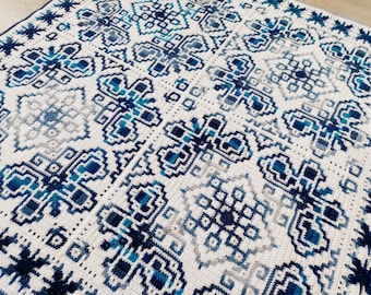 May include: A crocheted blanket with a geometric pattern in shades of blue and white.