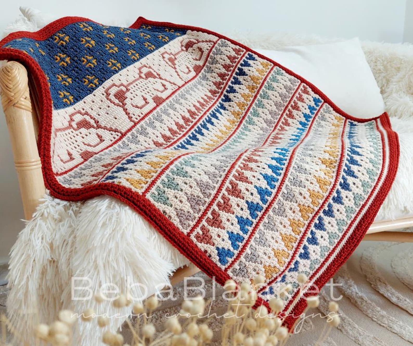 Mosaic crochet baby blanket with geometric rows and bear motifs in rich red, cream, blue, and gold tones