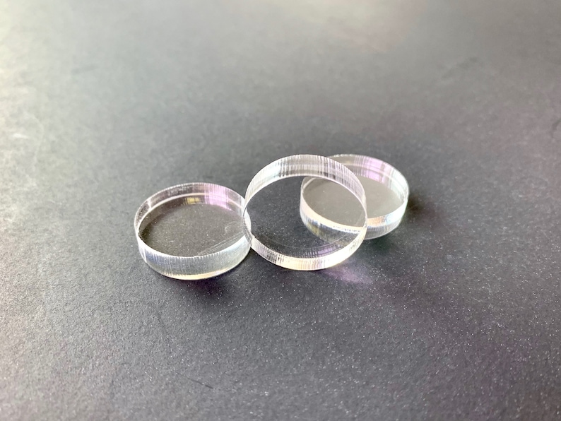 May include: Three clear acrylic circles stacked on top of each other. The circles are smooth and have a slight shine.