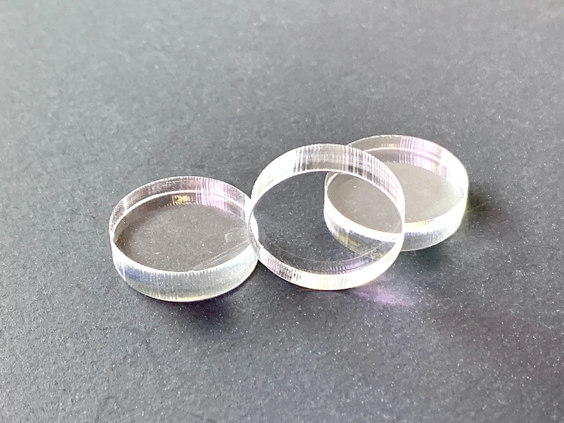 May include: Three clear acrylic circles, stacked on top of each other. The circles are smooth and have a slight shine.