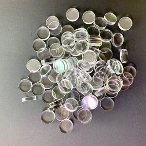 May include: A large pile of clear glass round discs, possibly for crafts or game pieces.