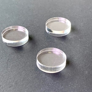 May include: Three clear acrylic circles, each with a slightly different diameter, are arranged on a dark gray surface.