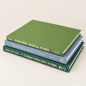 May include: A stack of three hardcover books about fly fishing. The top book is green with gold text reading Fishing Small Flies. The middle book is blue with gold text reading The Hatches Made Simple. The bottom book is dark green with gold text.