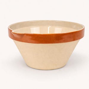 May include: A beige ceramic mixing bowl with a brown band around the rim. The bowl has a wide, sloped design and a small spout. This kitchenware item is suitable for mixing ingredients.