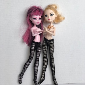 May include: Two fashion dolls with pink and blonde hair wearing black fishnet tights. The dolls are standing with their legs crossed.