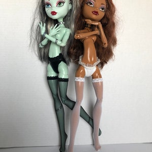 以下が含まれることがあります： 緑色の肌と黒い髪のモンスターハイ人形と、茶色の肌と茶色の髪のモンスターハイ人形の2体。両方の人形は黒と白のランジェリーとフィッシュネットのストッキングを着用しています。