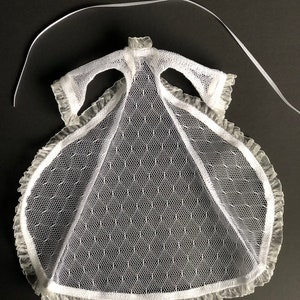 Pu&ograve; includere: Abito in tulle bianco con bordino in pizzo e un nastro da legare. L'abito &egrave; progettato per una bambola.