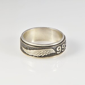 May include: A silver spinning ring with a black and silver wing design and the number "99" engraved on the side.