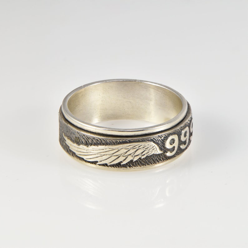 May include: A silver spinning ring with a black and silver wing design and the number "99" engraved on the side.