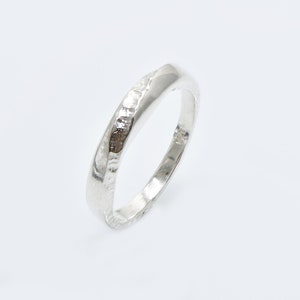 May include: A silver band ring with a textured surface.